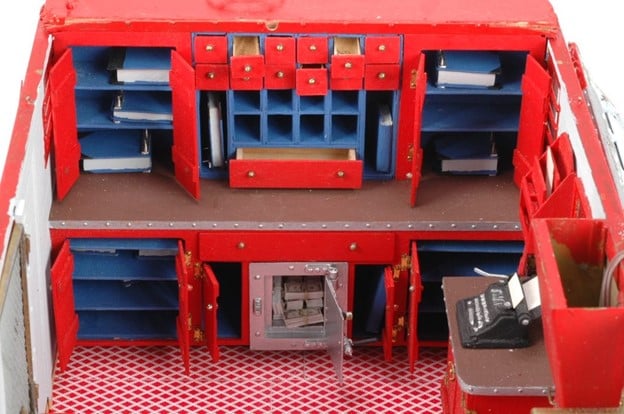 the interior view of a model wagon with shelves, open drawers, and an open safe with bundles of cash inside